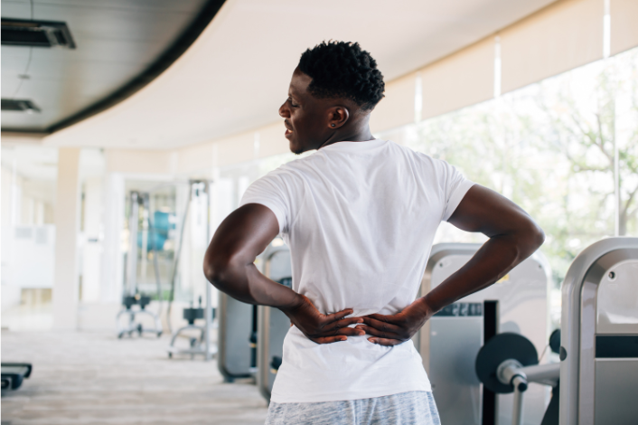 Man in a gym holding his lower back in pain